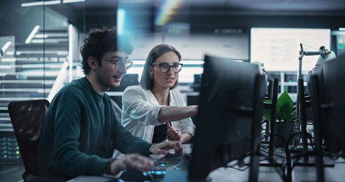 two colleagues looking at computer screen together 